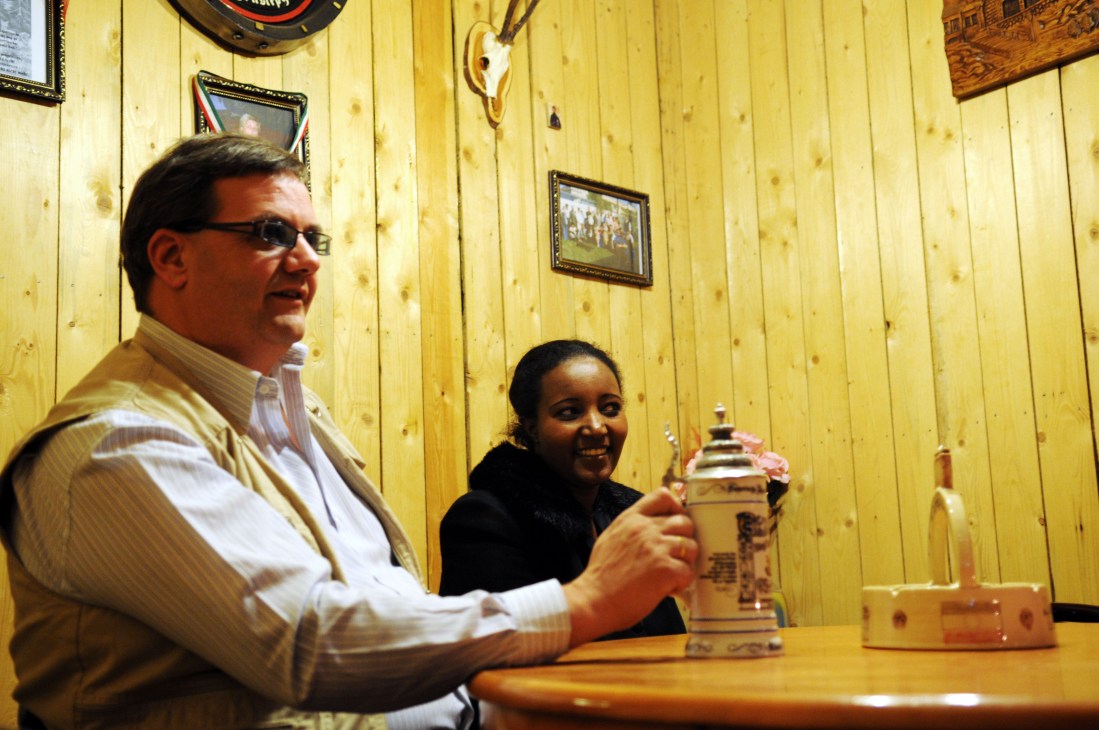 Günter Voelker, owner of Arbil's German restaurant, sits with his wife in a wood-paneled room.