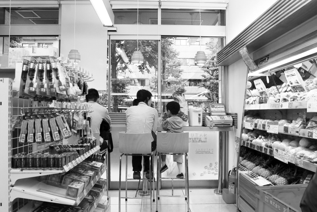 Interior of Natural Lawson convenience store with customers at counter and shelves of products.