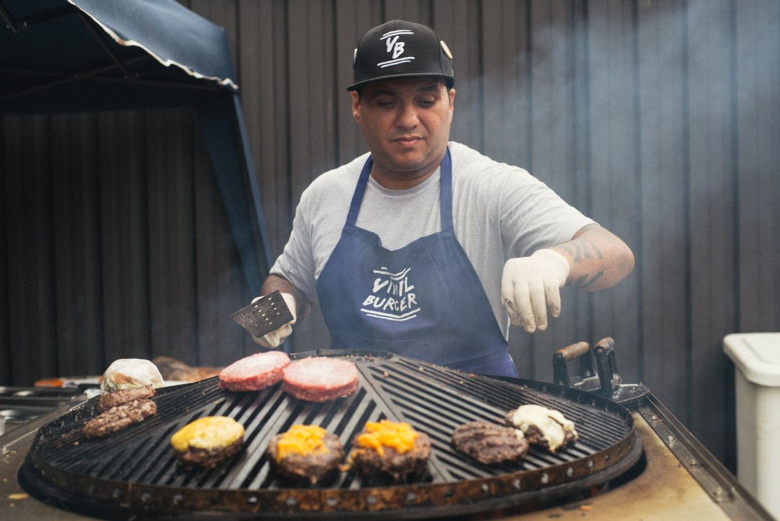 Chef flipping burgers on a grill at Butantan food park in São Paulo