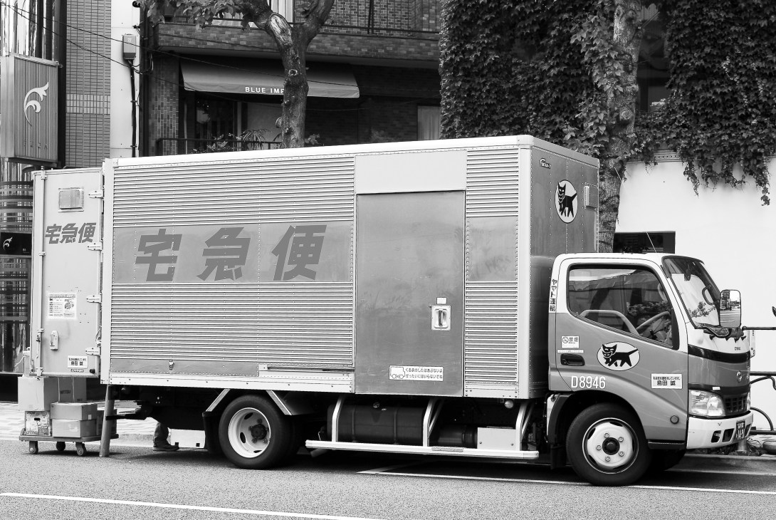 Yamato Takkyubin delivery truck parked on a Tokyo street with black cat logo visible.