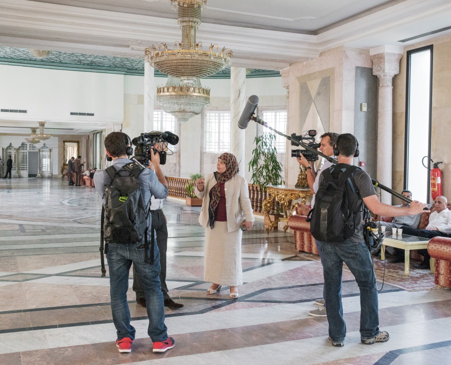 Tunisian politician Mehrezia Laâbidi-Maïza being interviewed by camera crew in an ornate parliament building corridor.