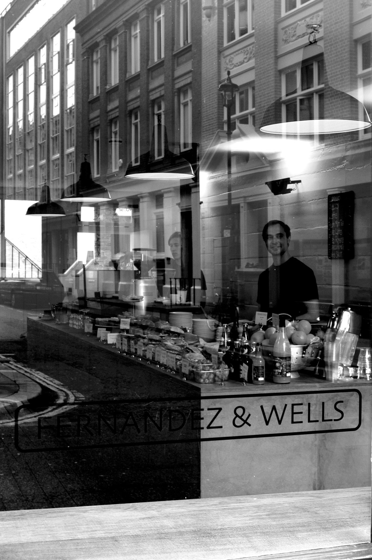 Man working behind counter at Fernandez & Wells deli on Soho's Lexington Street, London.