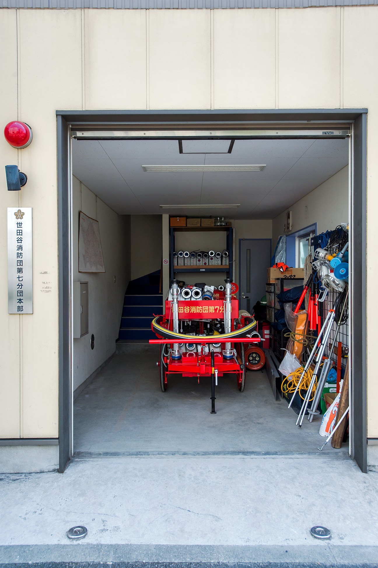 Interior of a volunteer fire station with red equipment and storage organized on shelves and walls.