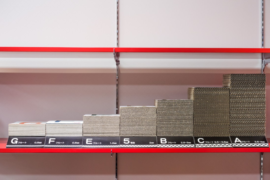 Crown Package cardboard samples displayed on red shelf showing varying thicknesses from 0.5mm to 3.5-4mm.