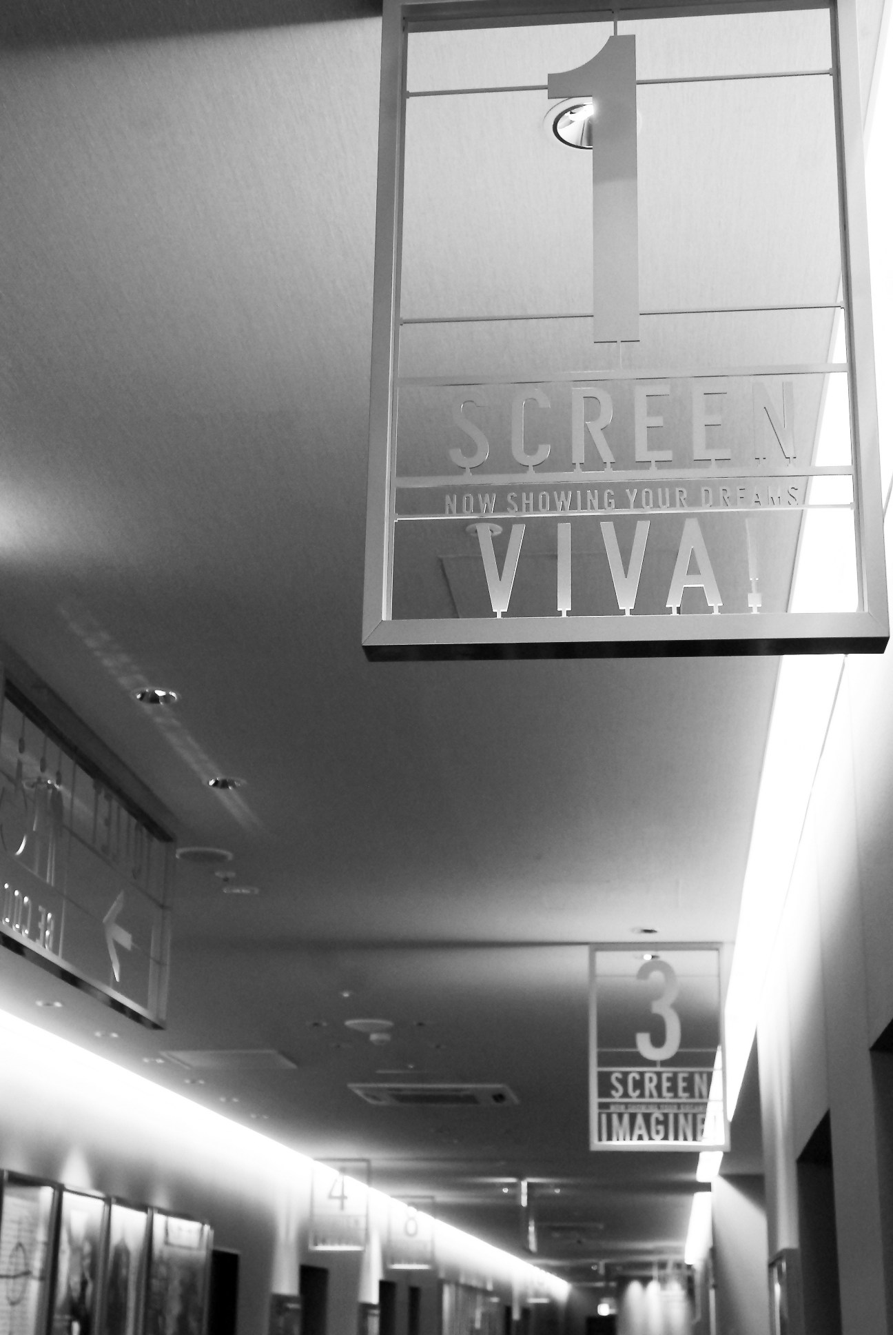 Black and white interior view of United Cinemas showing illuminated signage and modern architectural details.