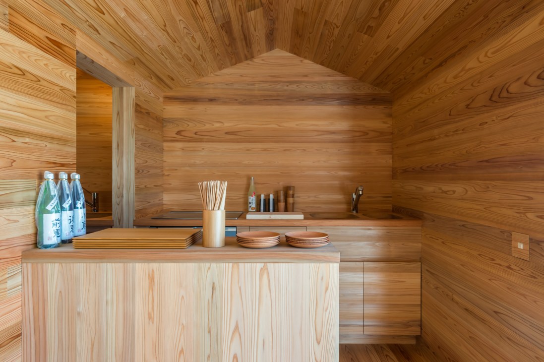 Interior of wooden structure with cedar walls and ceiling, counter with bottles, wooden vessels and decorative items.