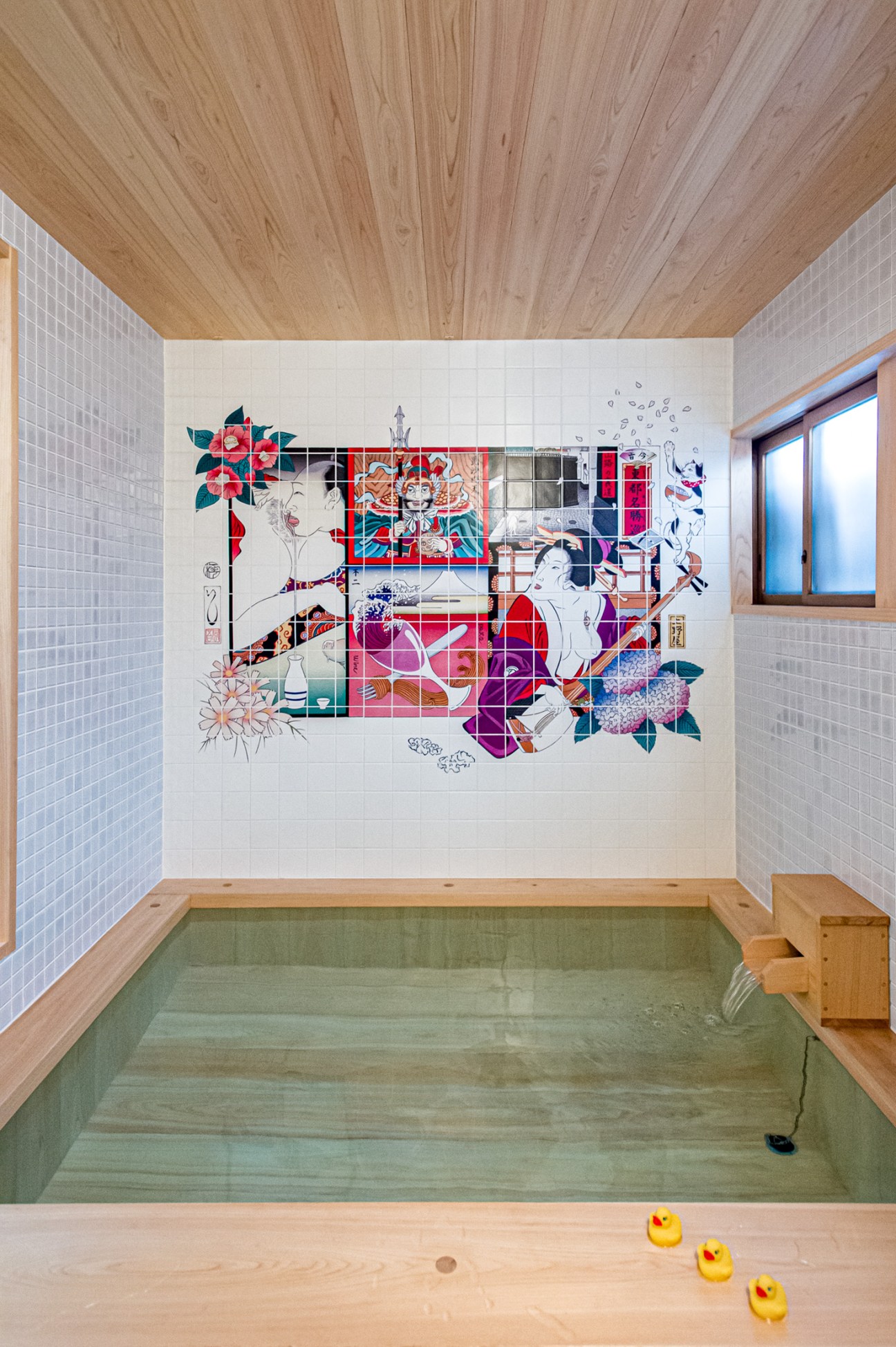 A hinoki cypress bathtub with colorful tile mural and wooden ceiling at Trunk House Tokyo.