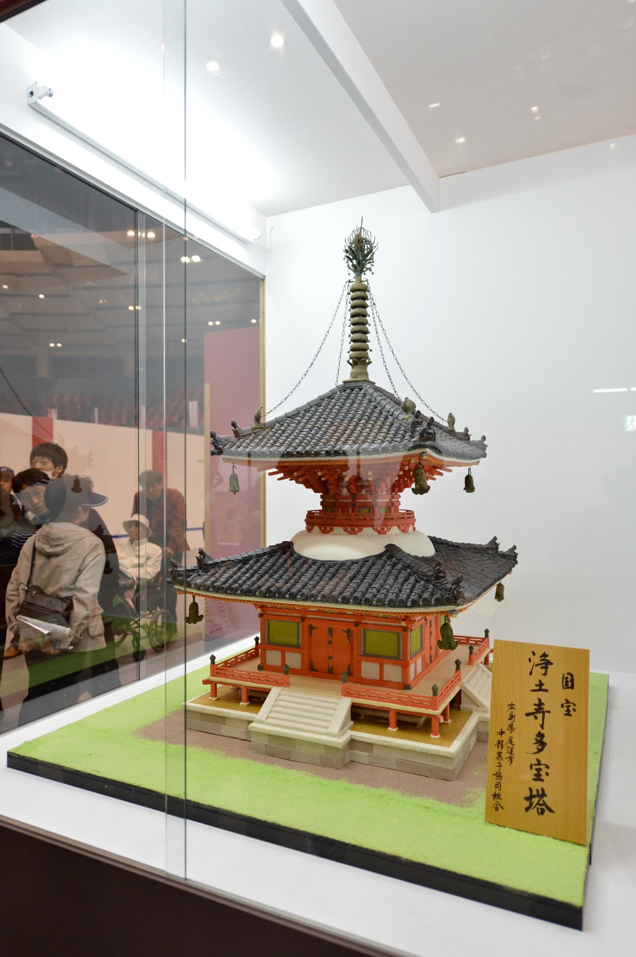 Intricate confectionery replica of a traditional Japanese pagoda with tiered roofs and ornate details displayed in a glass case.