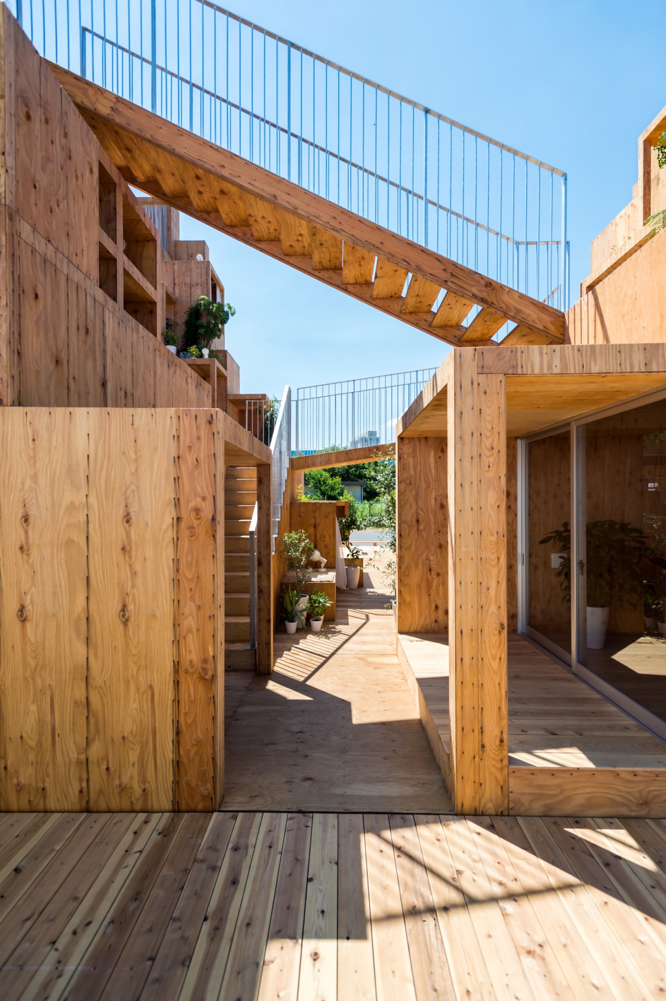 Wooden passageway with metal railings and architectural openings demonstrating the Rental Space Tower's shared community design.