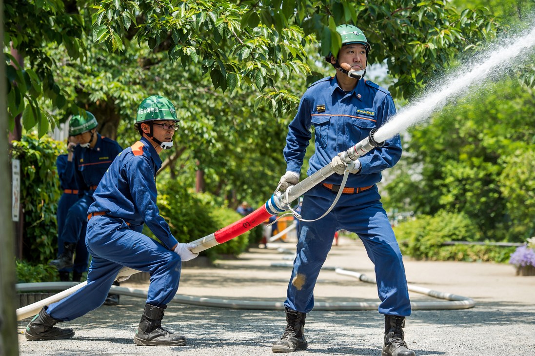 Tokyo volunteer firefighters training with hose equipment for tournament competition.