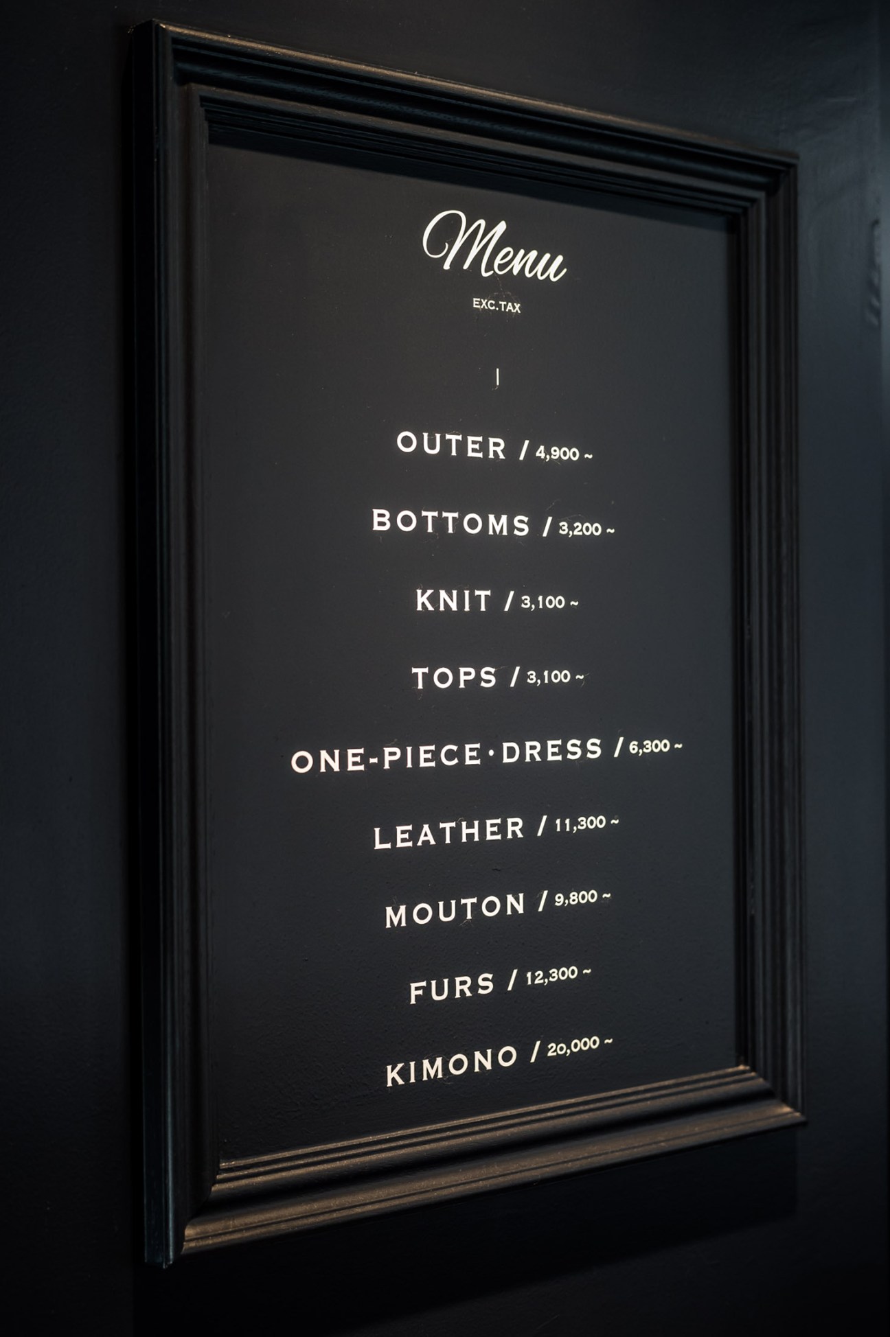 Framed menu board displaying Wardrobe Treatment's drycleaning services and prices in Japanese yen.