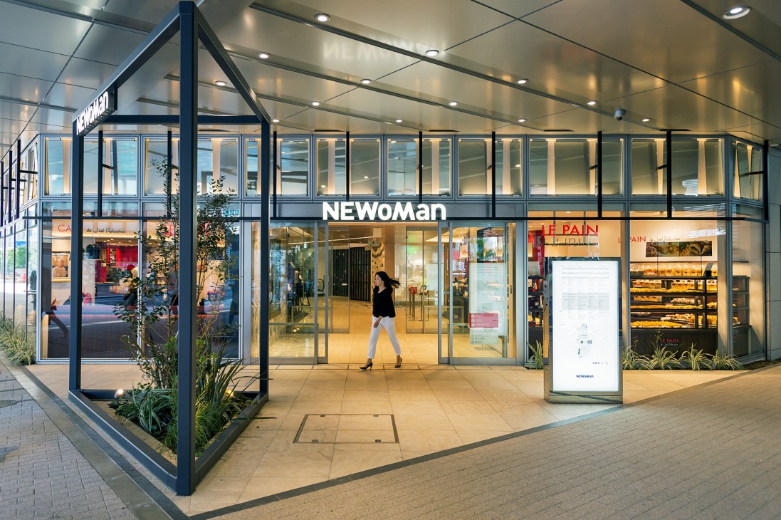 Newoman retail storefront at Shinjuku Station with glass facade and modern black framing.
