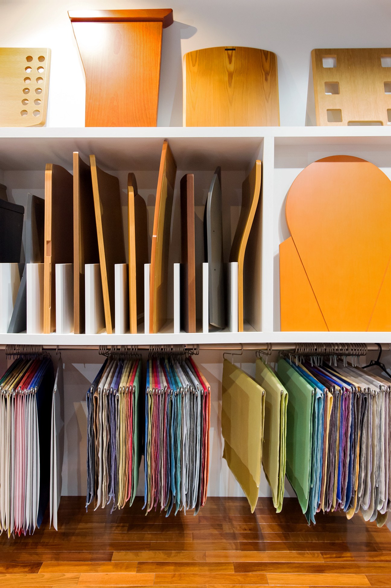 Kotobuki Seating's wooden chair backs and colorful fabric swatches displayed on shelves and hanging rod.