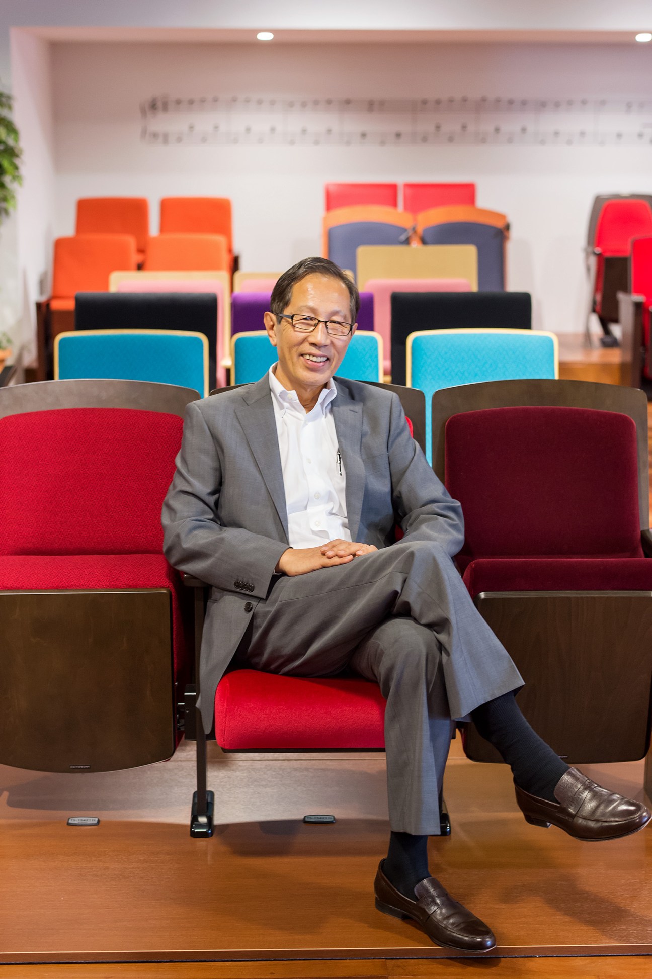Shigeyuki Fukasawa sits among colorful seat samples at Kotobuki Seating headquarters in Tokyo.
