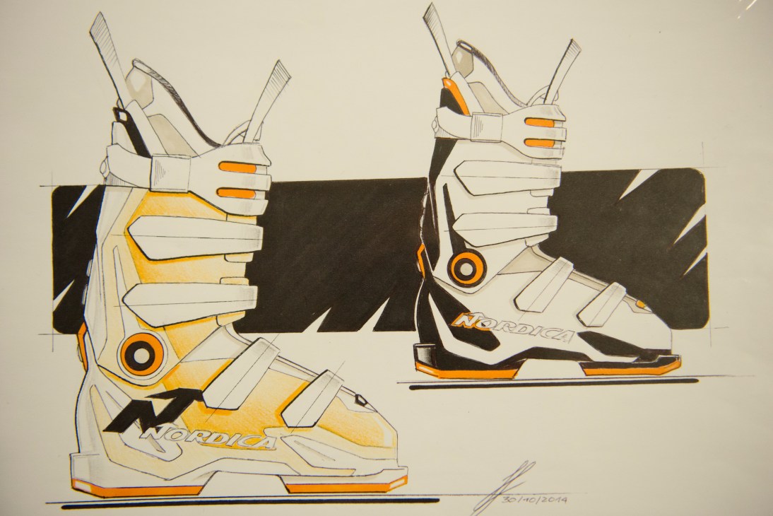 Technical drawing of two Nordica ski boots shown from side and front views with white, orange and black coloring