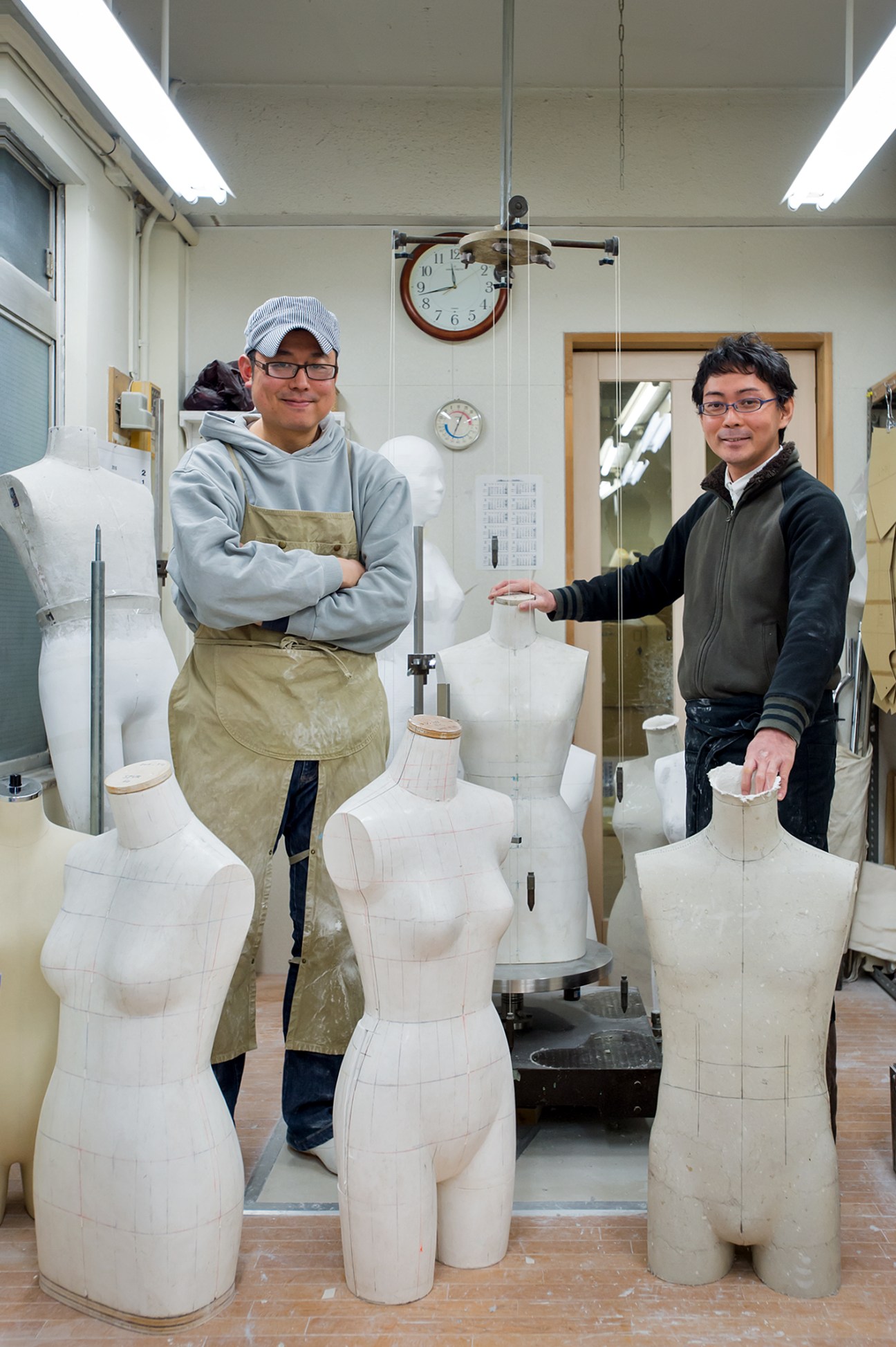 Takahiro Suga and Yujiro Uzura stand among mannequin torsos in Kiiya's atelier workshop in Tokyo.