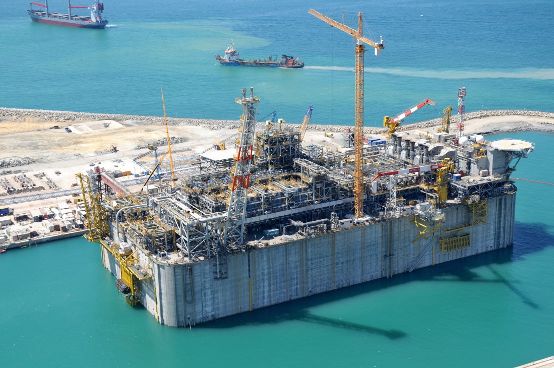 Aerial view of a large offshore gas terminal platform in the Adriatic Sea with construction cranes and support vessels.