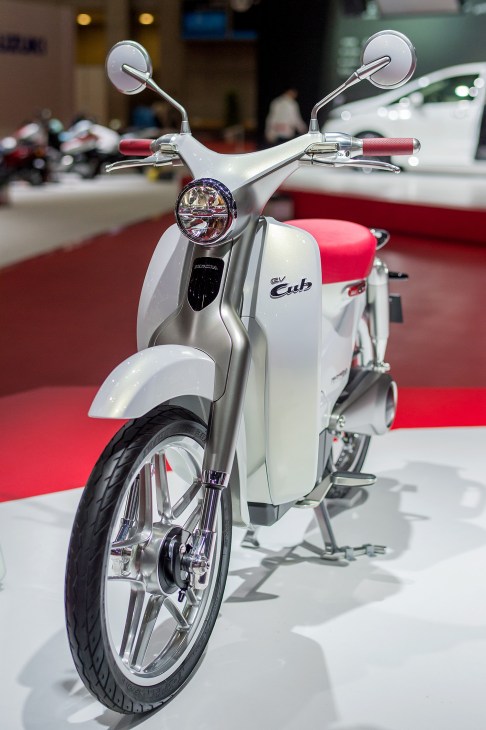 Honda's metallic-white EV-Cub electric scooter displayed at Tokyo Motor Show with round headlamp and curved frame.