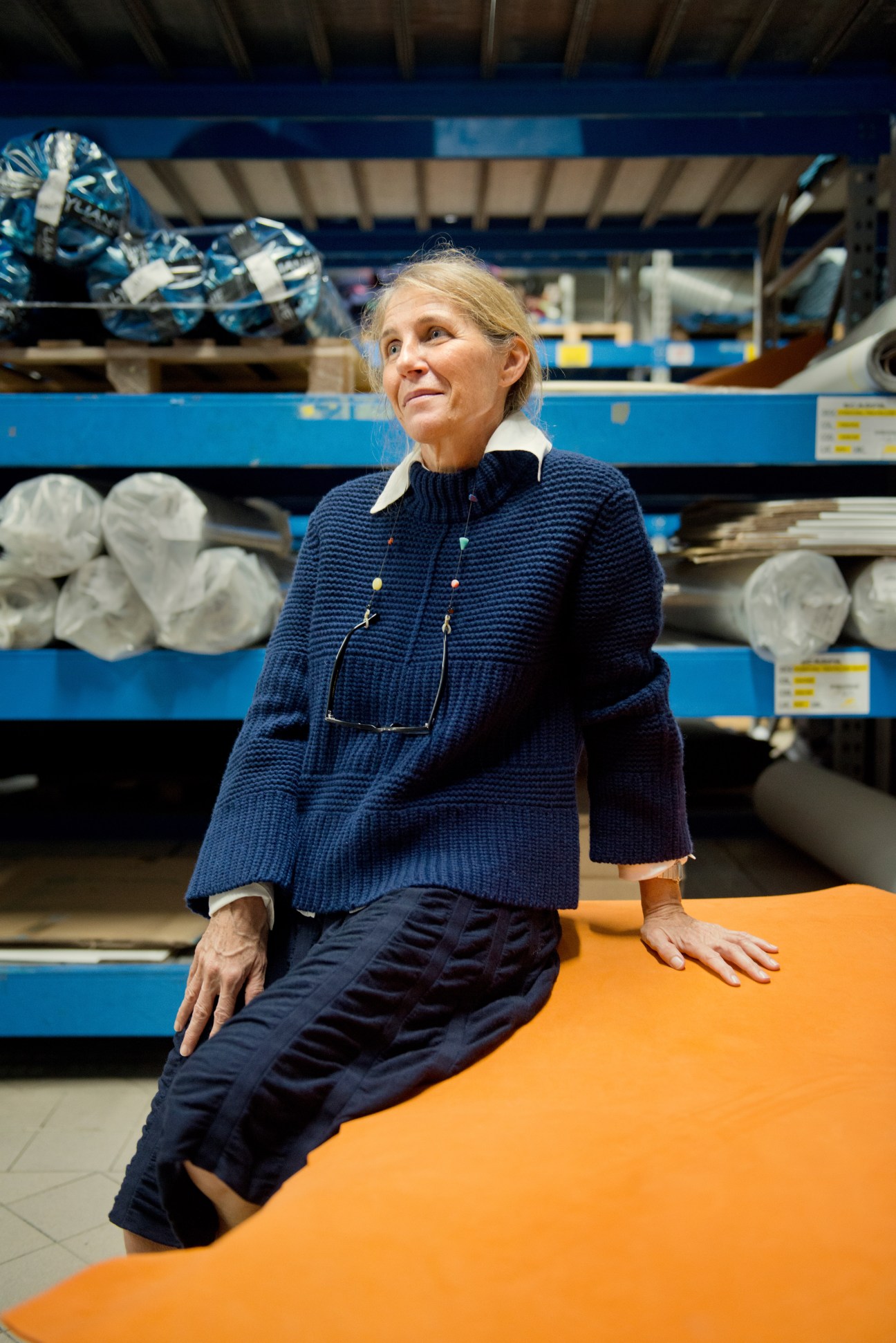 Cristina Parisotto, Scarpa's co-founder, sits in the company's warehouse surrounded by rolls of material and shelves of shoe components.