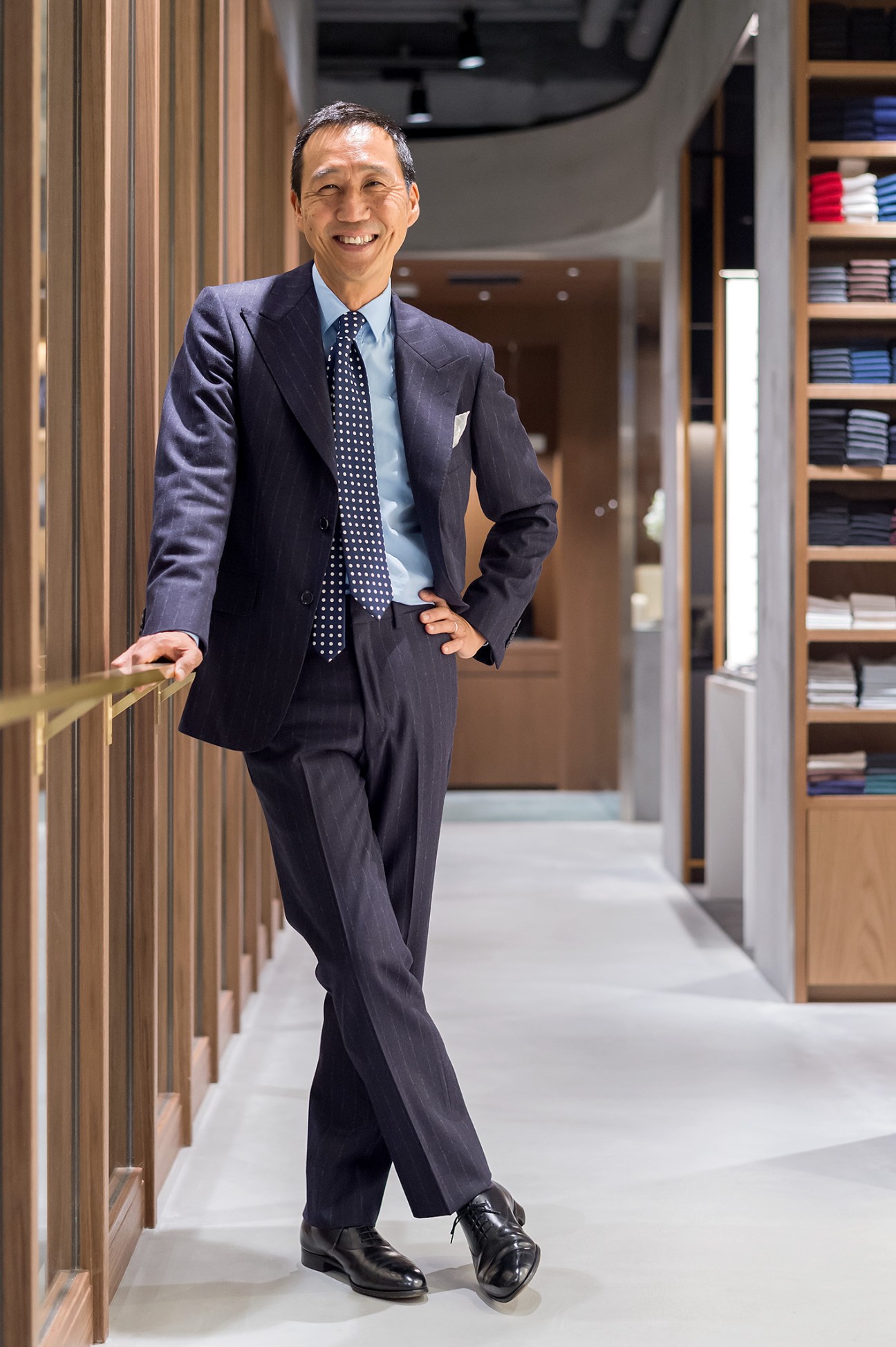 Yasuto Kamoshita in navy suit and polka dot tie standing in modern retail space with wooden fixtures