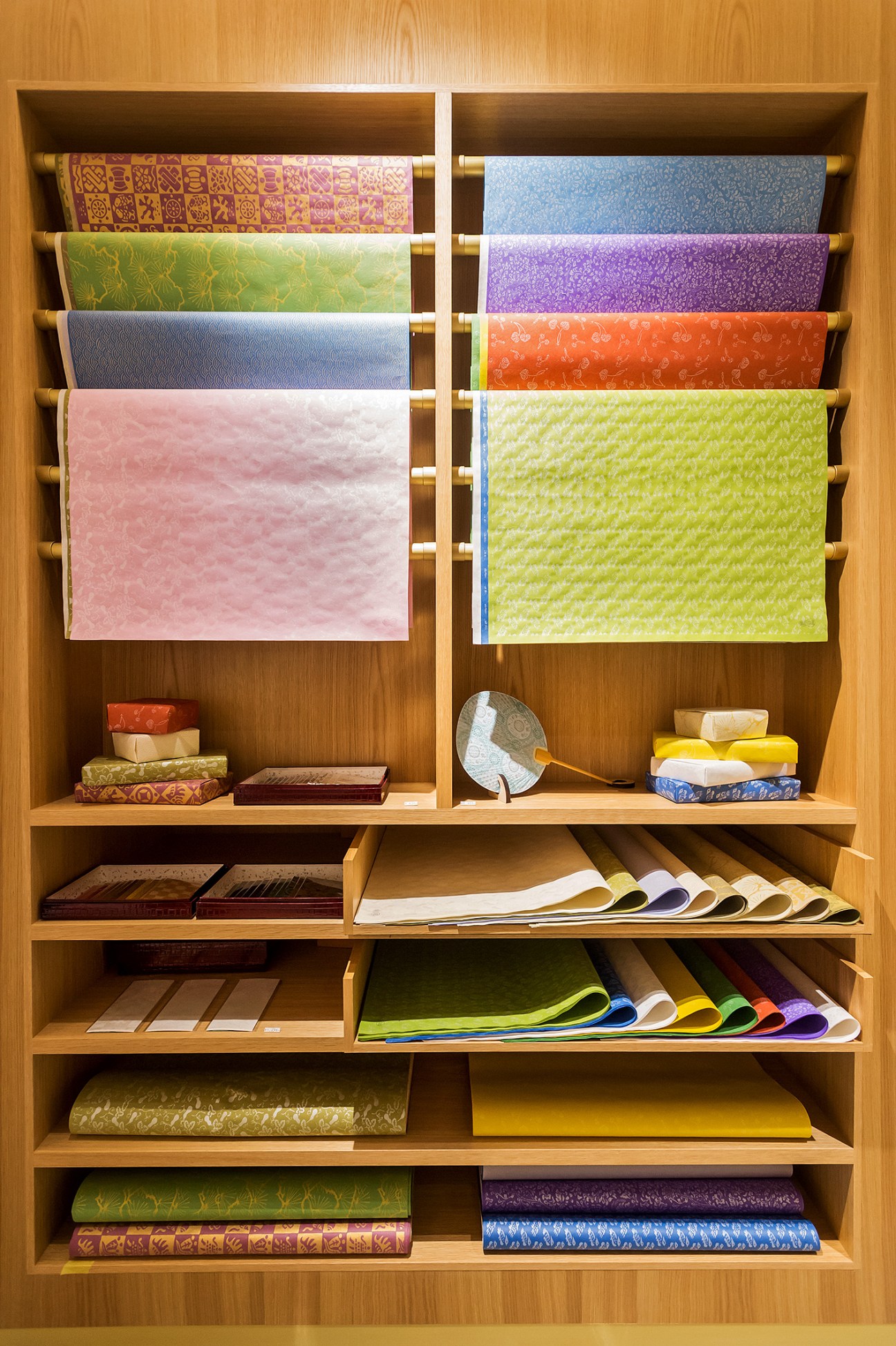 Colorful hand-printed paper by Karacho displayed in wooden shelving unit with various patterns and colors