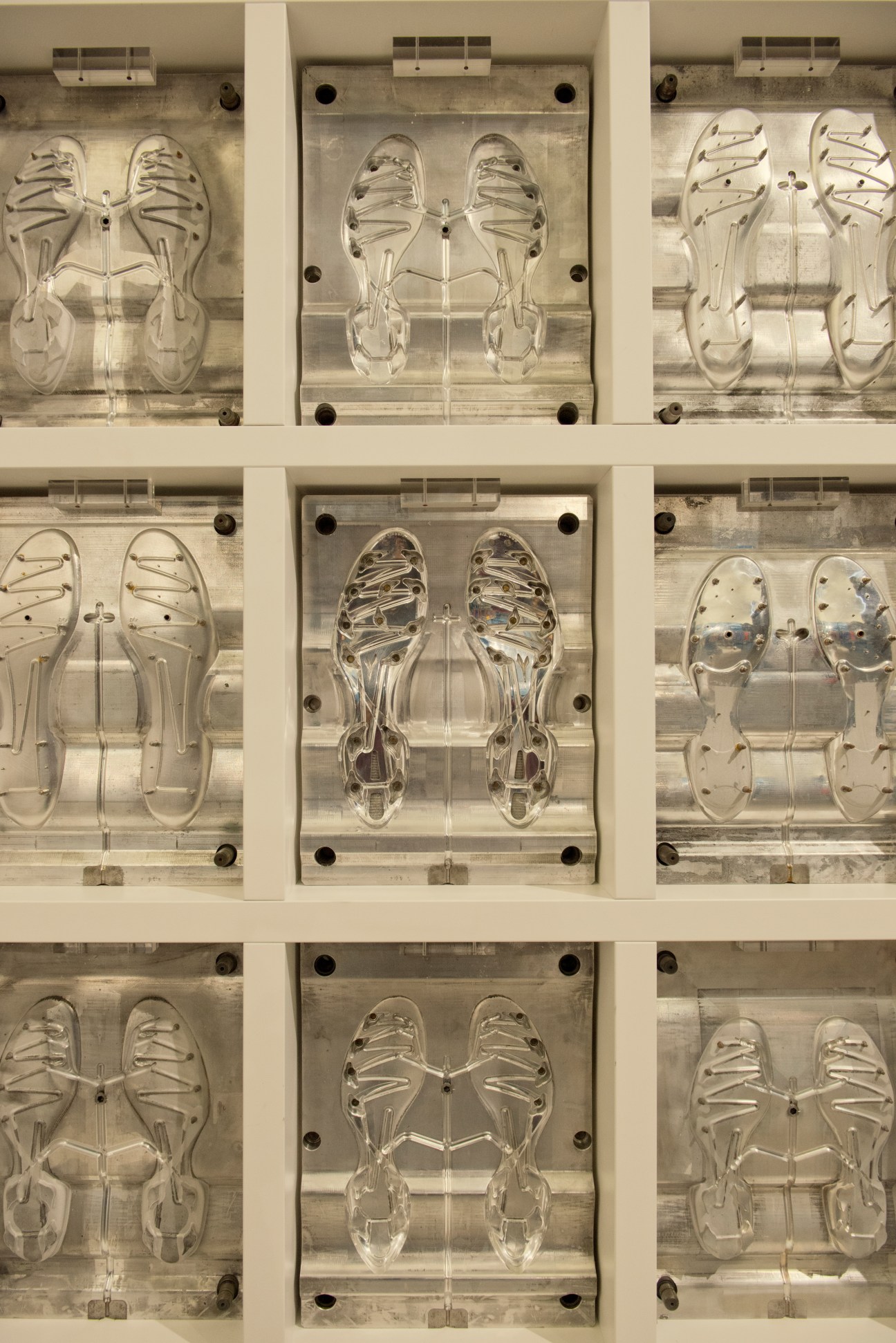 Display of clear silicone shoe sole molds showing studded sole patterns for athletic footwear production.
