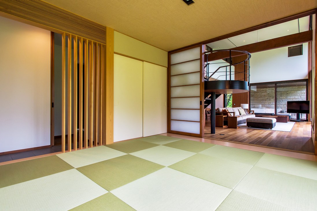 Spacious tatami rooms with green and cream-colored mats opening to a modern living room with wooden furniture and large windows.