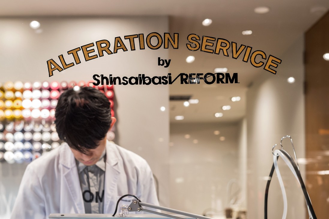 Worker in white coat operating alteration equipment at Shinsaibashi Reform service counter