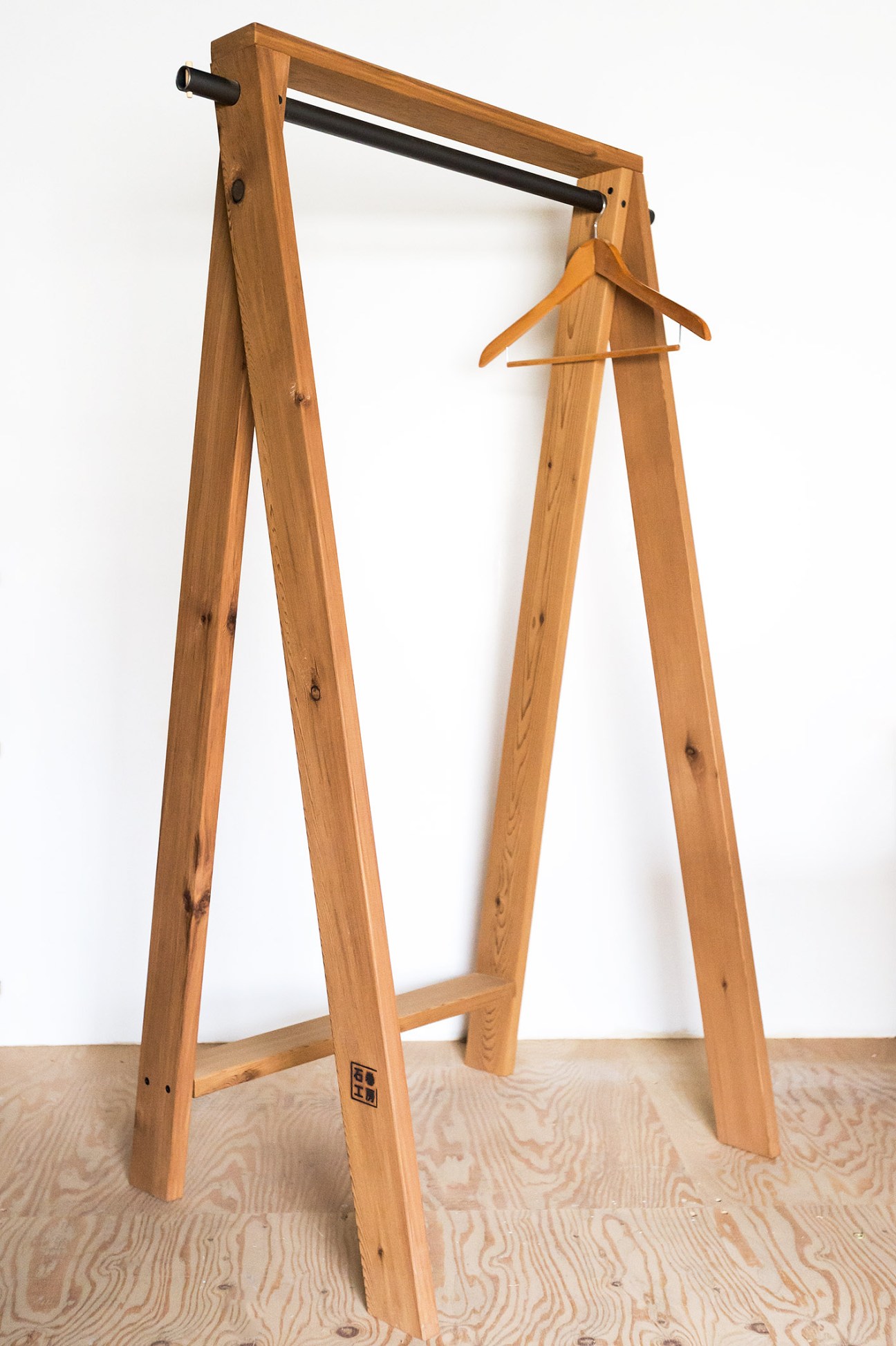 Wooden A-frame clothes hanger with cedar construction and black metal rod, designed by Torafu Architects.