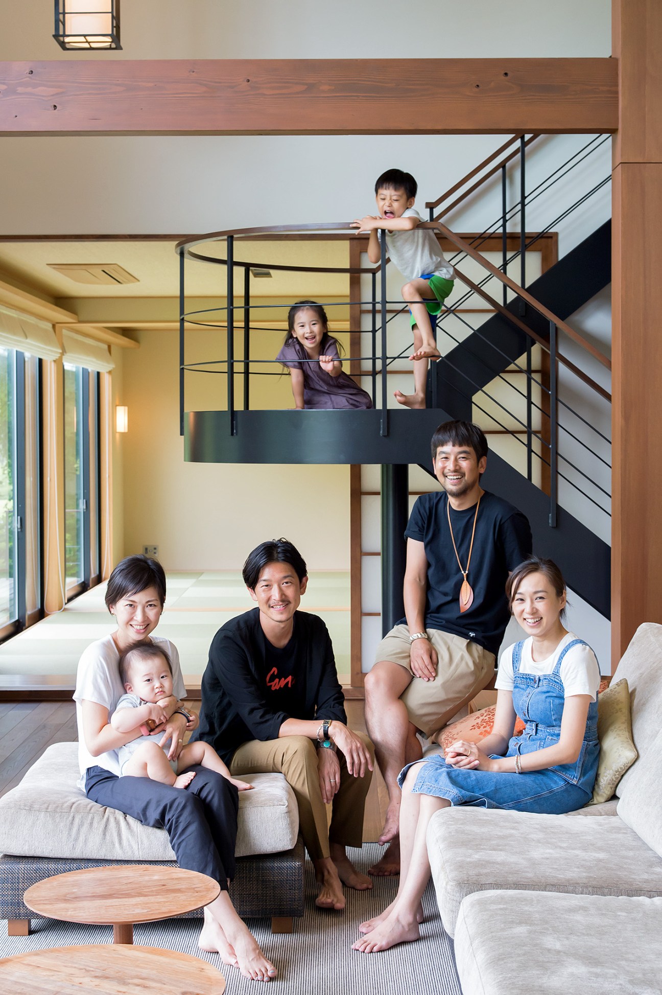 Two families with children pose together in a modern wooden interior with a mezzanine level.