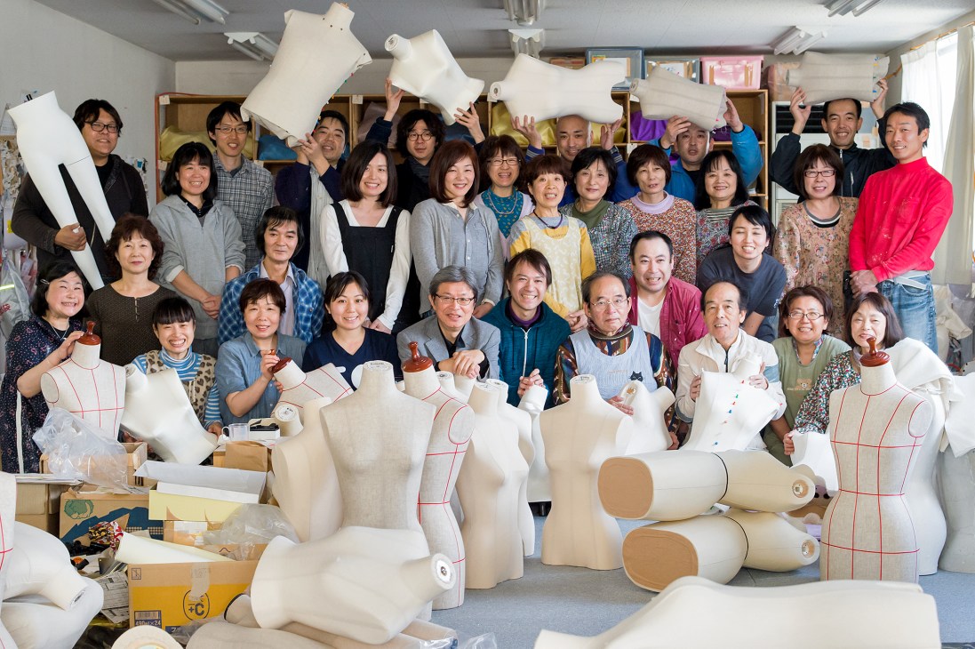 Large group of Kiiya factory staff posing together with white mannequin parts and forms in Kanagawa.