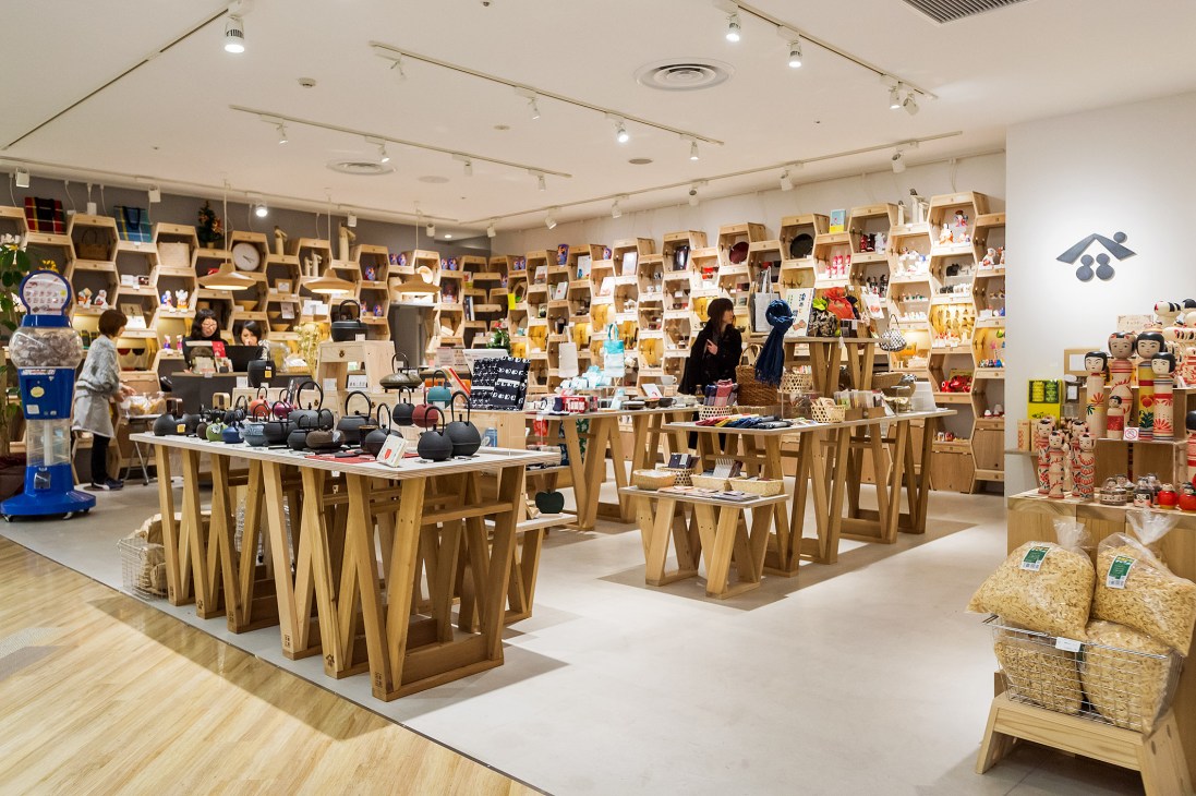 Interior of Tohoku Standard shop with wooden Carry Stools displaying regional crafts and products on shelves.