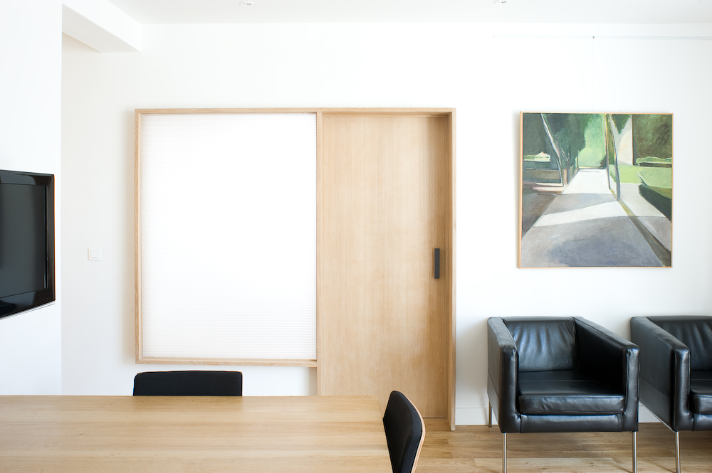 Modern office interior with pale oak door, translucent panel, leather chairs and whiteboard designed by Ciguë.