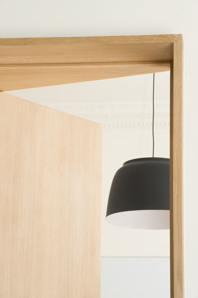 Light oak wooden door frame with translucent white panel and black pendant lamp visible beyond.