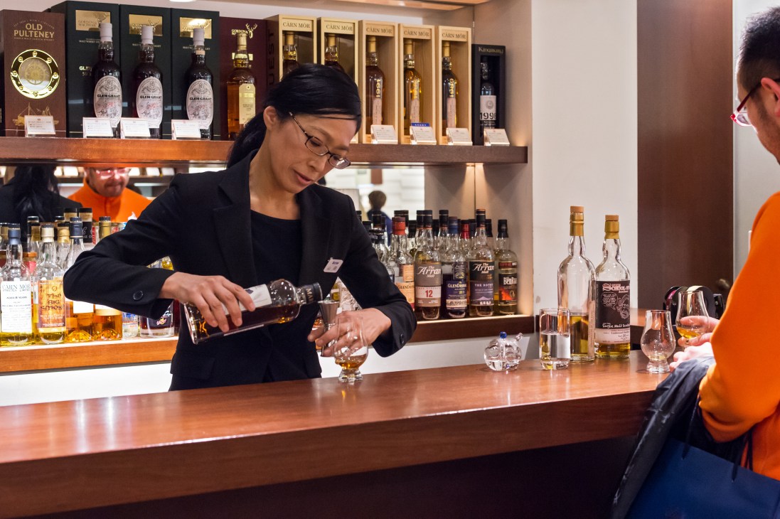 A staff member pours whisky at Isetan's alcohol counter during a tasting session.