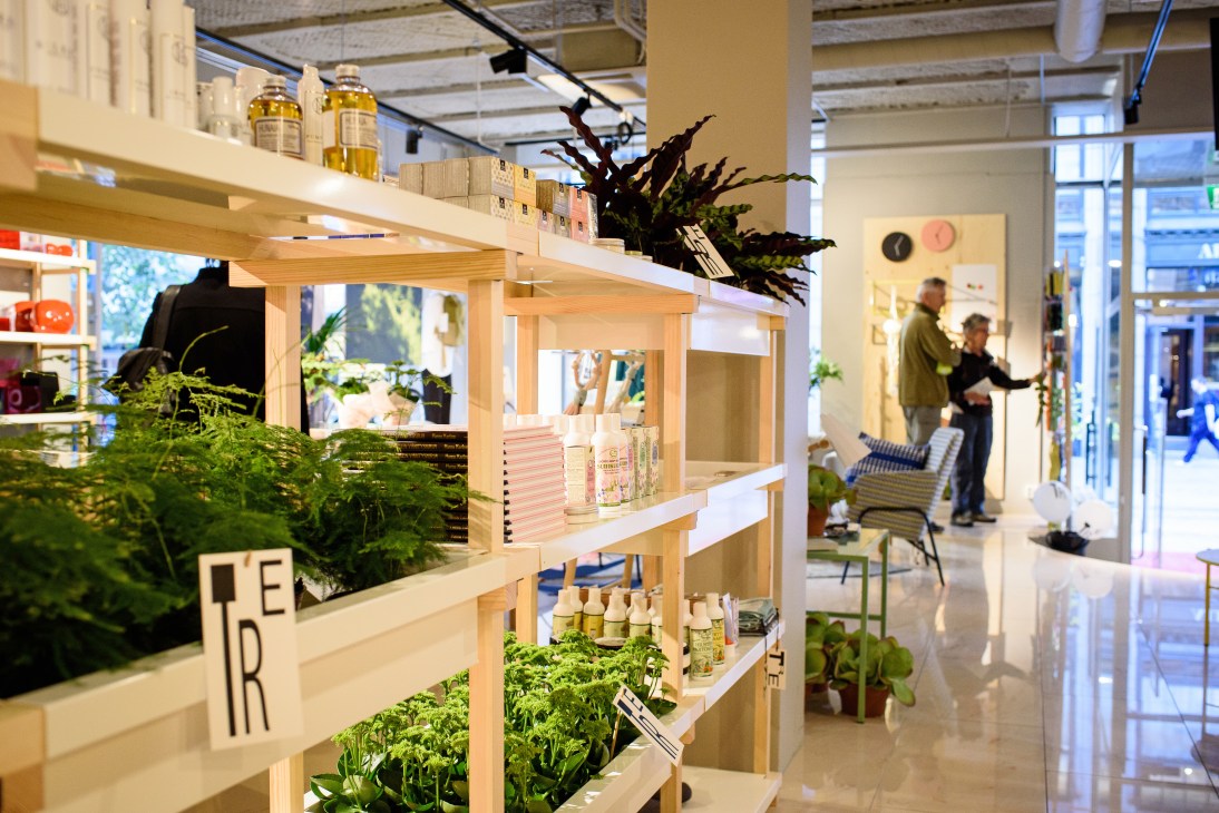 Interior of TRE shop in Helsinki showing wooden shelving displays with plants, products and merchandise.