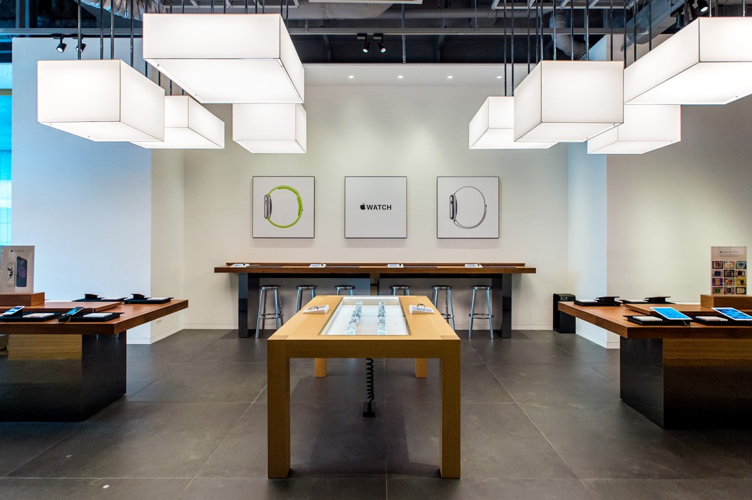 Apple Watch display section with minimalist wood tables and floating ceiling lights at Tsutaya Electrics.
