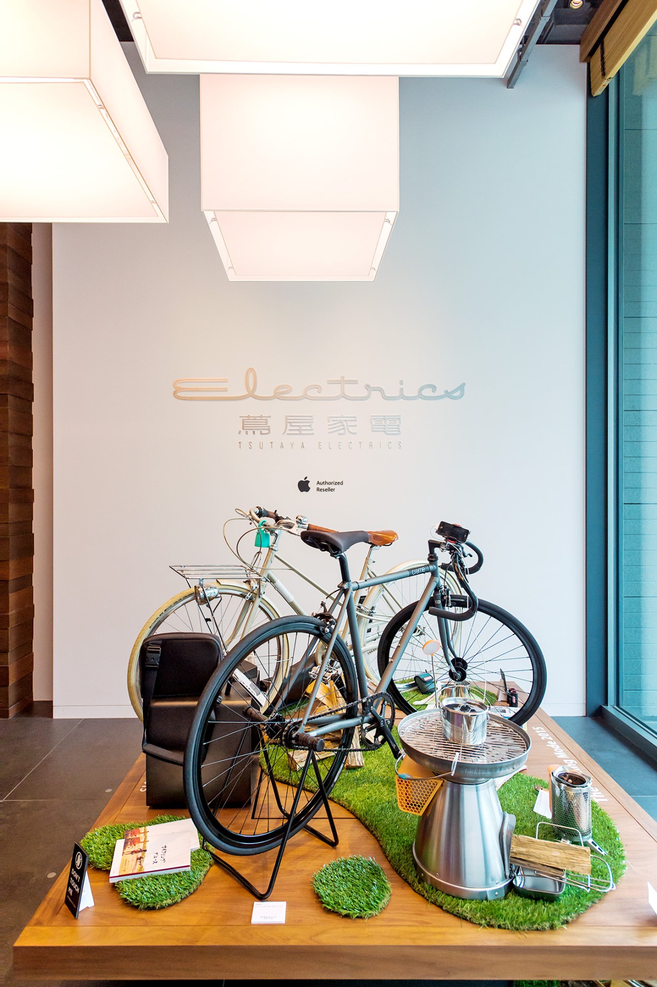 Bicycles from Motovelo bike shop displayed in Tsutaya Electrics with artificial grass and accessories.