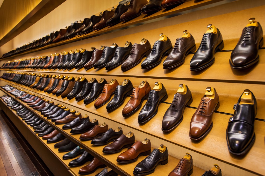 Men's dress shoes displayed on illuminated yellow shelving at Isetan department store.