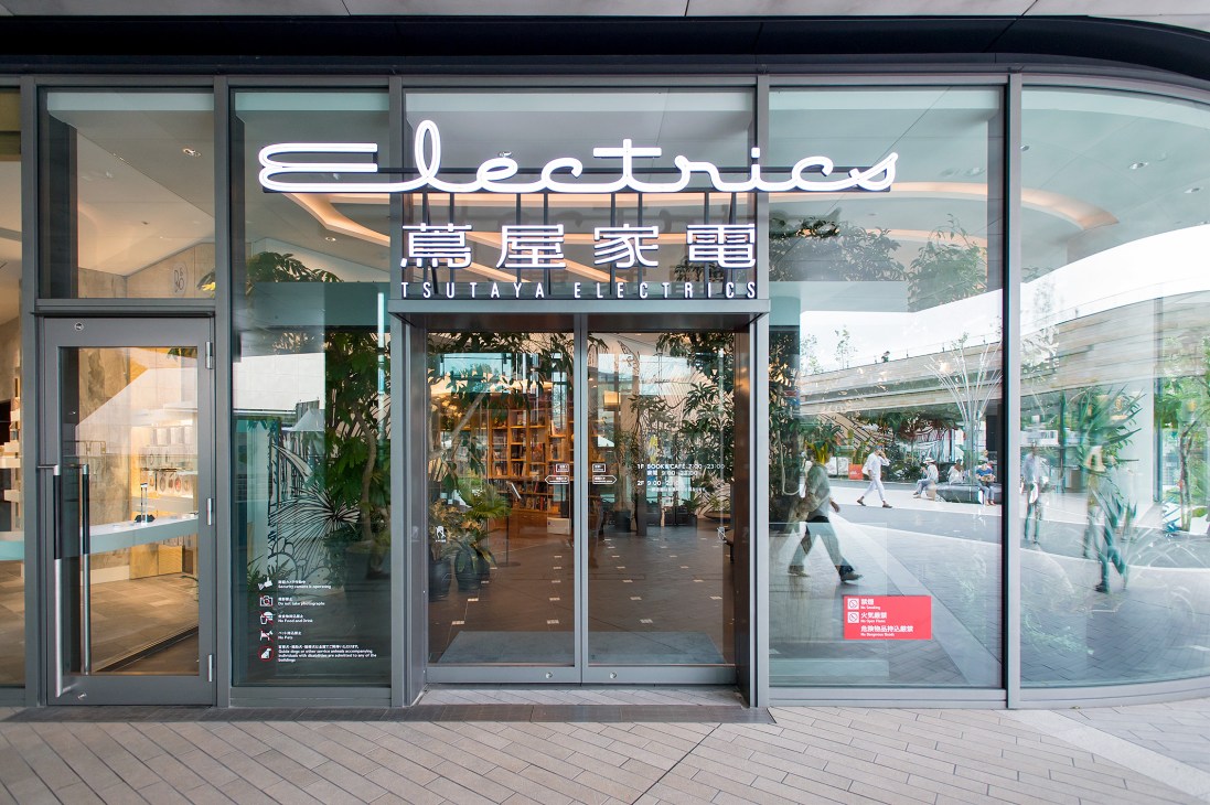 Tsutaya Electrics storefront with neon signage and glass facade in a modern shopping development.