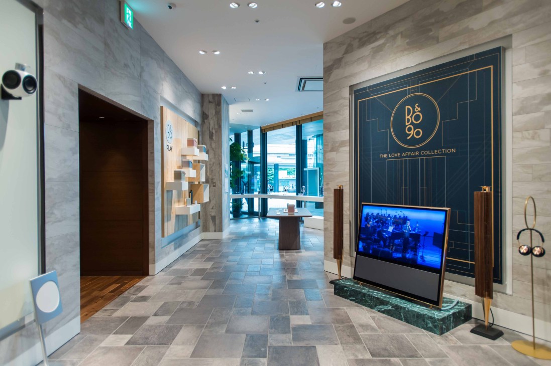 Bang & Olufsen shop entrance within Tsutaya Electrics, featuring a dark blue storefront with gold geometric branding and a video display.