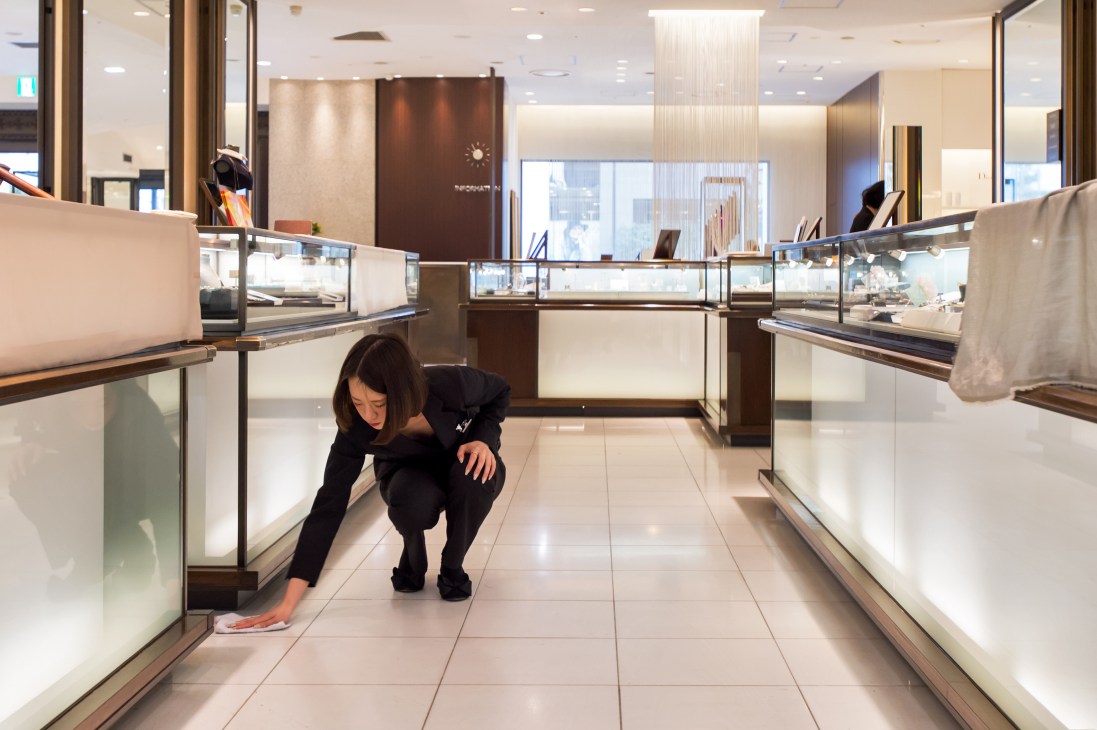 Staff member cleaning the floor of Isetan department store with cloth and cleaning solution.