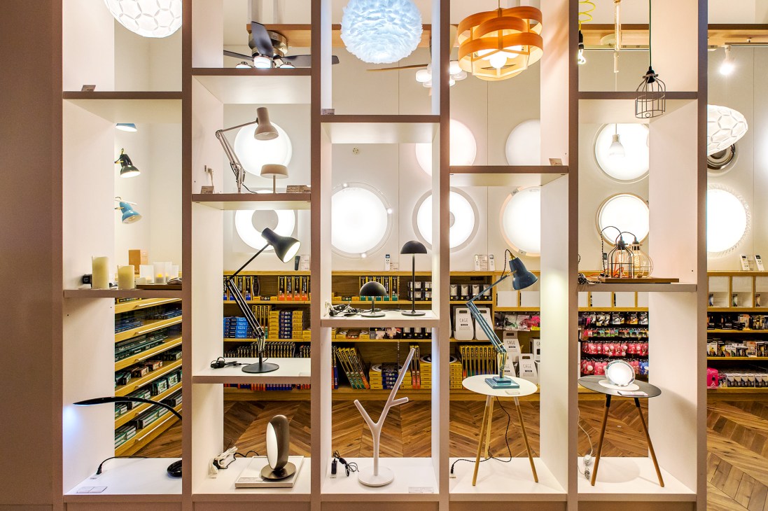 Tsutaya Electrics lighting section displays various pendant lamps and desk lamps in illuminated wooden display cases.