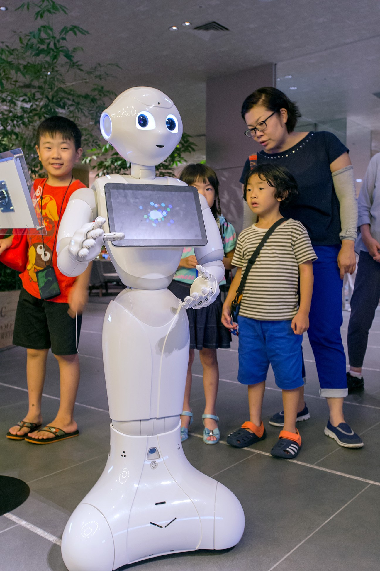 Pepper the robot interacts with children and an adult in Tsutaya Electrics store.