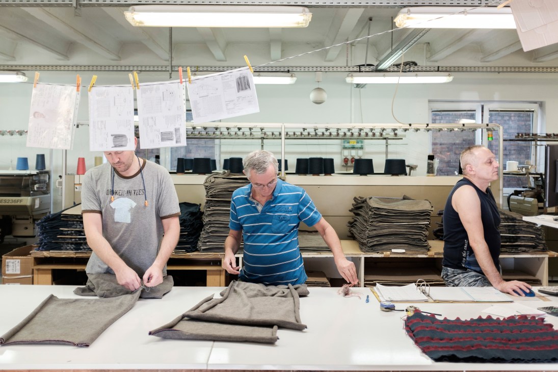 Three workers examine and fold knitwear at the Sima-Tex factory workstation.