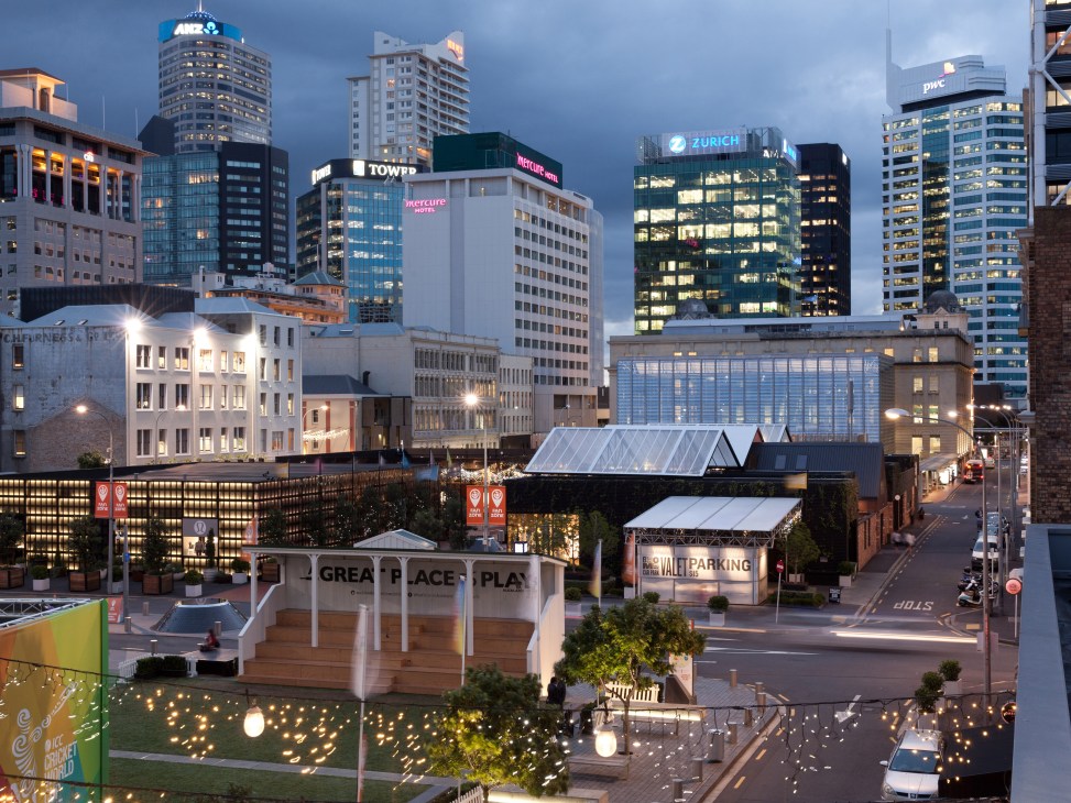 Auckland city skyline at dusk with illuminated office buildings and urban streetscape.