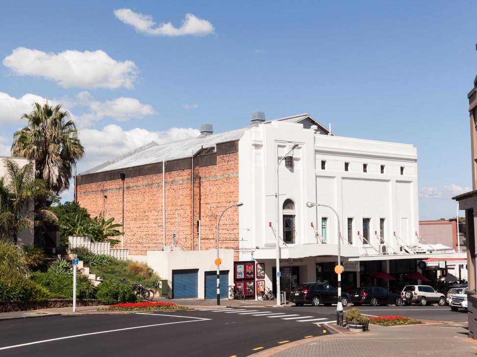 The Vic, a 1930s cinema in Devonport, Auckland, with white facade and red brick building beside it.
