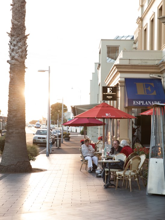 Outdoor café seating with red umbrellas at the Esplanade Hotel on Queens Parade in Devonport, Auckland.