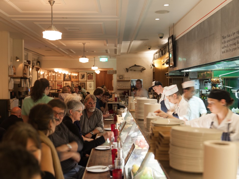 Interior of Federal Delicatessen in Auckland with customers seated at counter and chefs working in open kitchen.