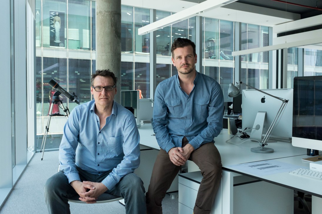 Dominic Wanders and Richard Wagner sit in a modern office with glass walls and contemporary furnishings.